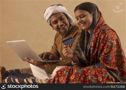 A RURAL HUSBAND WIFE SITTING TOGETHER AND DOING ONLINE TRANSACTIONS