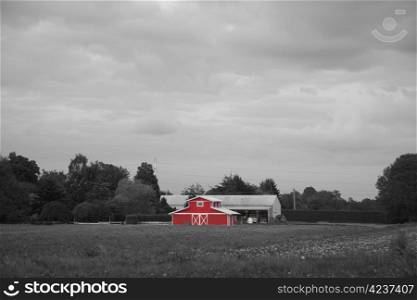 A rural landscape with a farm building in red in the midst of a black and white farmer&rsquo;s field
