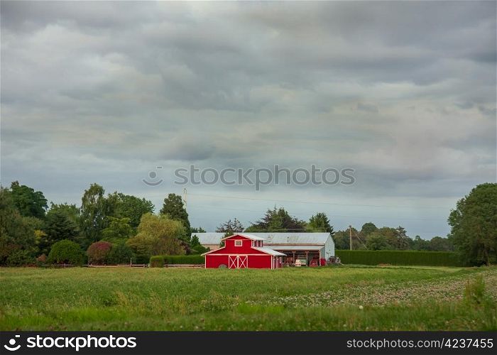 A rural landscape with farm buildings in the midst of a farmer&rsquo;s field