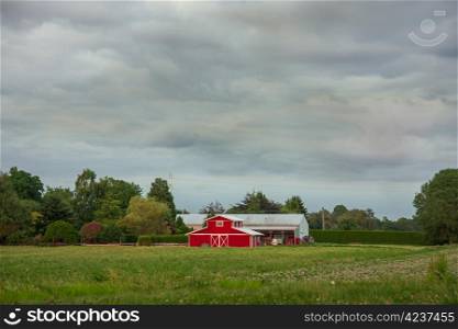 A rural landscape with farm buildings in the midst of a farmer&rsquo;s field