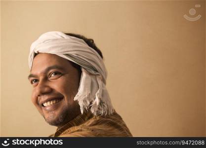 A RURAL MAN WITH DHOTI WRAPPED AROUND HIS HEAD LOOKING ABOVE AND SMILING