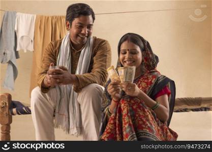 A RURAL WIFE HAPPILY COUNTING MONEY WHILE HUSBAND SITS BESIDE
