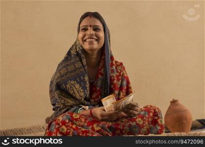 A RURAL WOMAN HAPPILY SITTING WITH MONEY IN HAND 