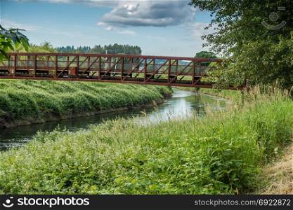 A rusted metal bridge spans the Green River in Kent, Washington.