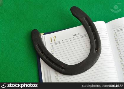 A rusty horse shoe displayed in a open dairy on the day 17 March - St Patrick's day - on a green background