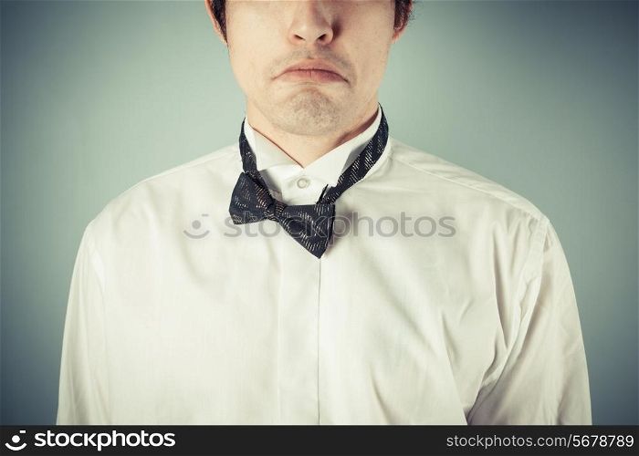 A sad young man wearing a messy bow tie