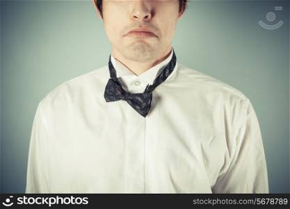 A sad young man wearing a messy bow tie
