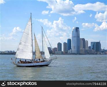 A sail boat on the water with a city behind