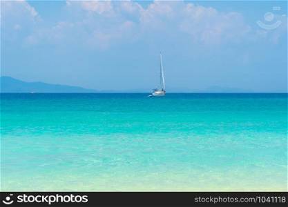 A sailboat in blue turquoise seawater near Phuket island in summer season during travel holidays vacation trip. Andaman ocean, Thailand. Tourist attraction with blue cloud sky.