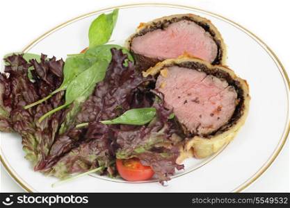 A salad of lollo rosso, spinach and tomato with slices of beef wellington, or boeuf en croute
