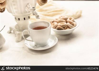 a samovar with bagels and hot tea on the white tablecloth