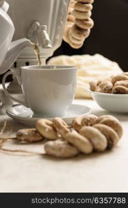 a samovar with bagels and hot tea on the white tablecloth