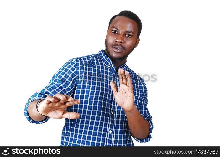 A scared looking young black man in a blue shirt with his arm&rsquo;s raisedstanding isolated for white background.