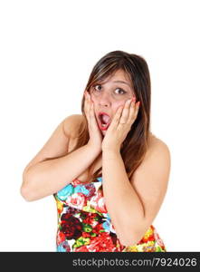 A scared young woman in a colourful short summer dress standing in profileholding her hands on her face, isolated for white background.