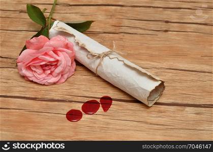 A scroll of paper tie up with rope and a pink rose and three drops of blood
