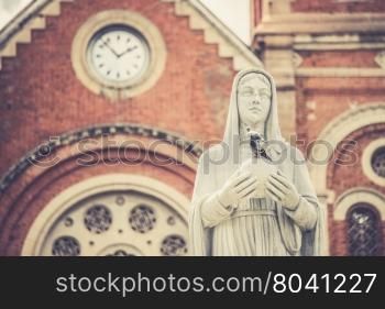 A sculpture of the Virgin Mary in front of the Notre-Dame Saigon Basilica in Ho Chi Minh City, Vietnam (Vintage filter effect used)