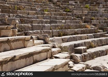 A section of seats in the old Roman theater at Ephesus near Izmir in Turkey. There are two aisles leading up through the tiers of stone seats.