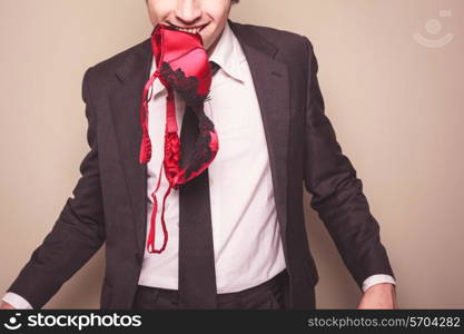 A seductive businessman has a bra in his mouth