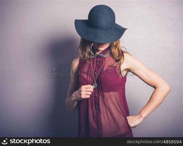 A seductive young woman is wearing a hat and a transparent shirt