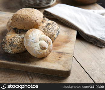 A selection of fresh Bread Rolls, on a wooden bread board.