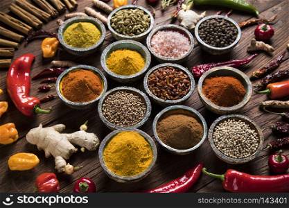 A selection of various colorful spices on a wooden table in bowl. Wooden table of colorful spices