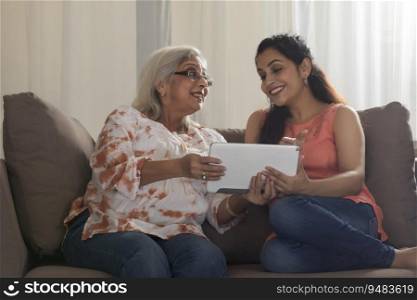 A SENIOR ADULT MOTHER AND DAUGHTER HAPPILY USING A TABLET