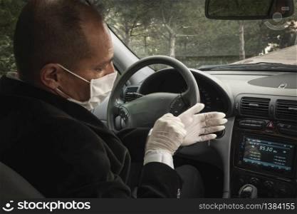 A senior adult trying to wear his surgical gloves in his car for protection against coronavirus