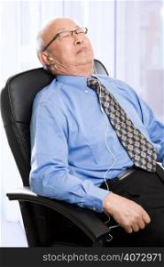 A senior asian businessman sleeping and listening to music at the office