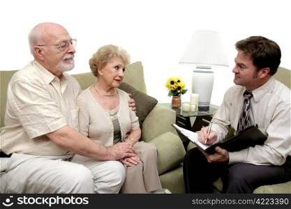 A senior couple speaking with a marriage counselor. Could also be a salesman in their home. Isolated on white with focus on couple.