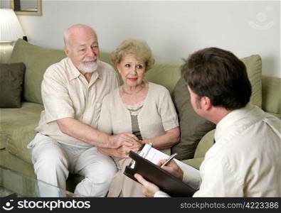 A senior couple talking with a marriage counselor. Could also be a salesman in their home.