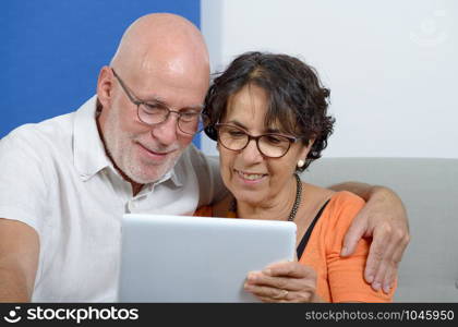 a senior couple using a tablet and smiling