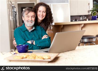 A senior father with his middle age daughter using a laptop