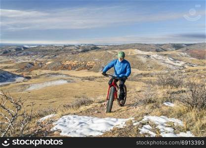 a senior male riding a fat bike on Cheyenne Rim in Red Mountain Open Space, late fall scenery with some snow