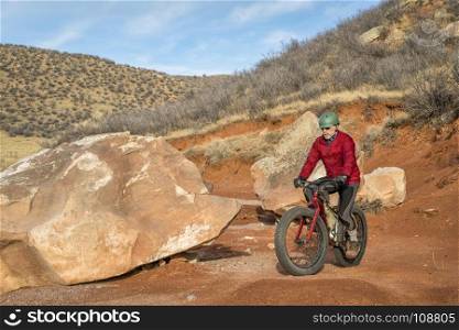 a senior male riding a fat bike on mountain desert trail in Red Mountain Open Space in Colorado, late fall scenery