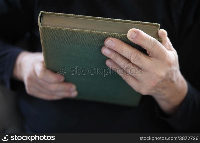 A senior man holds an old book.