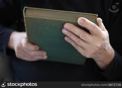 A senior man holds an old book.