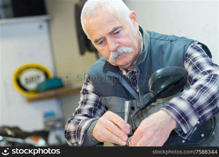 a senior man repairing motorbike outdoor