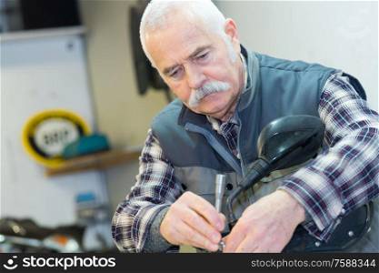 a senior man repairing motorbike outdoor