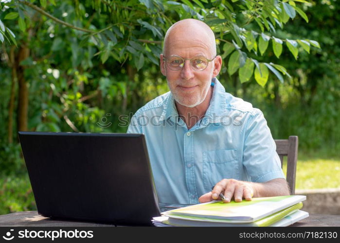 a senior man using laptop in the garden