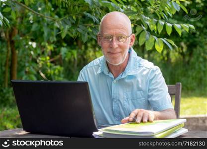 a senior man using laptop in the garden