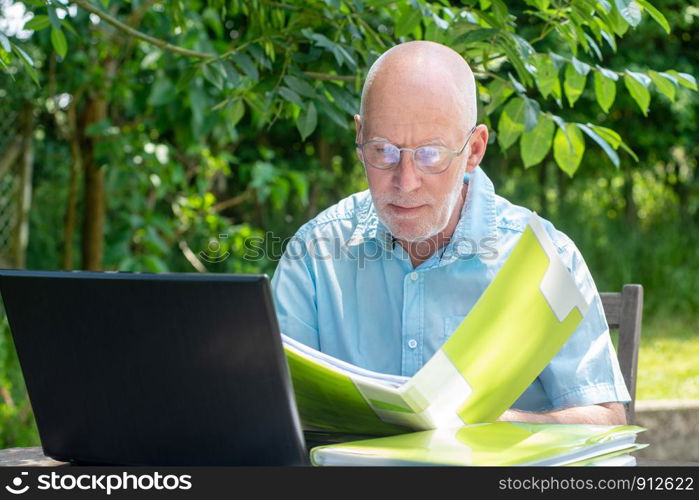 a senior man using laptop in the garden