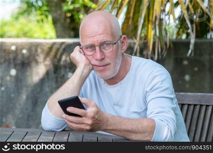a senior man using phone in the garden