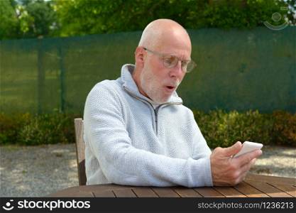 a senior man using the mobile phone outside