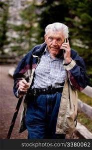 A senior talking on a cell phone outdoors in the forest