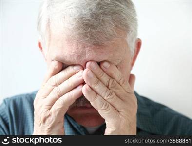 a senior with both hands over his eyes