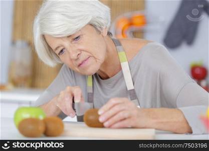 a senior woman chopping tomatoes