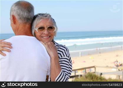 a senior woman hugging her husband near the sea