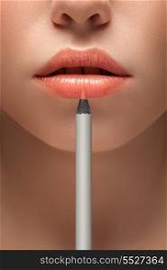 A sensual picture of woman lower face with makeup pencil in front of lips.