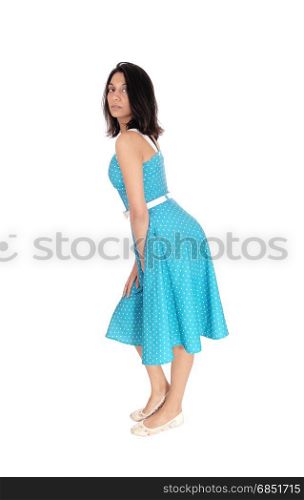 A serious gorgeous young woman standing in full length in a blue dressin profile, isolated for white background.