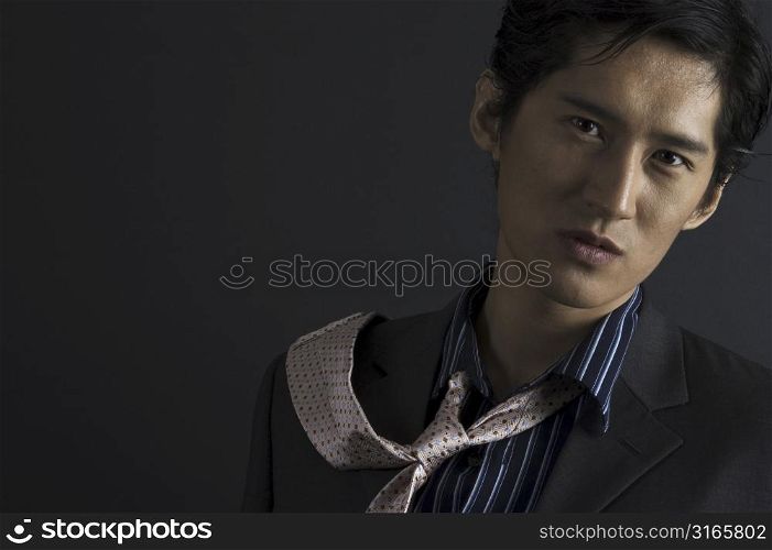 A serious-looking asian model flicks his tie over his shoulder
